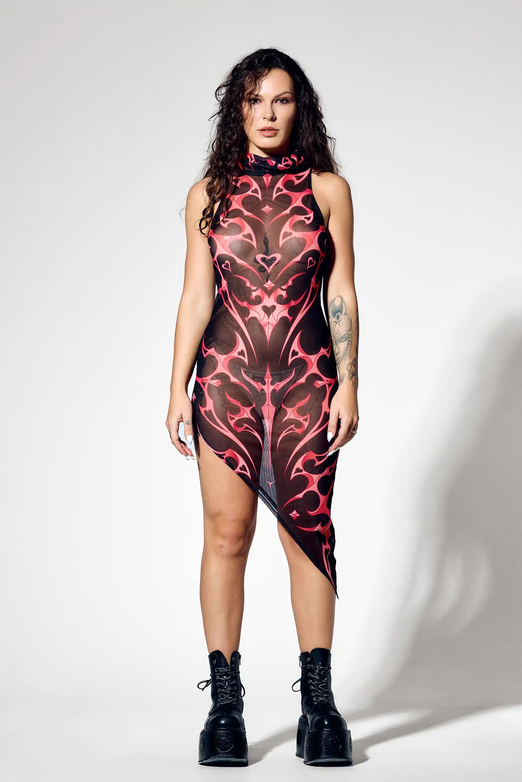 Woman wearing pink tribal mesh dress with asymmetrical hem and platform boots