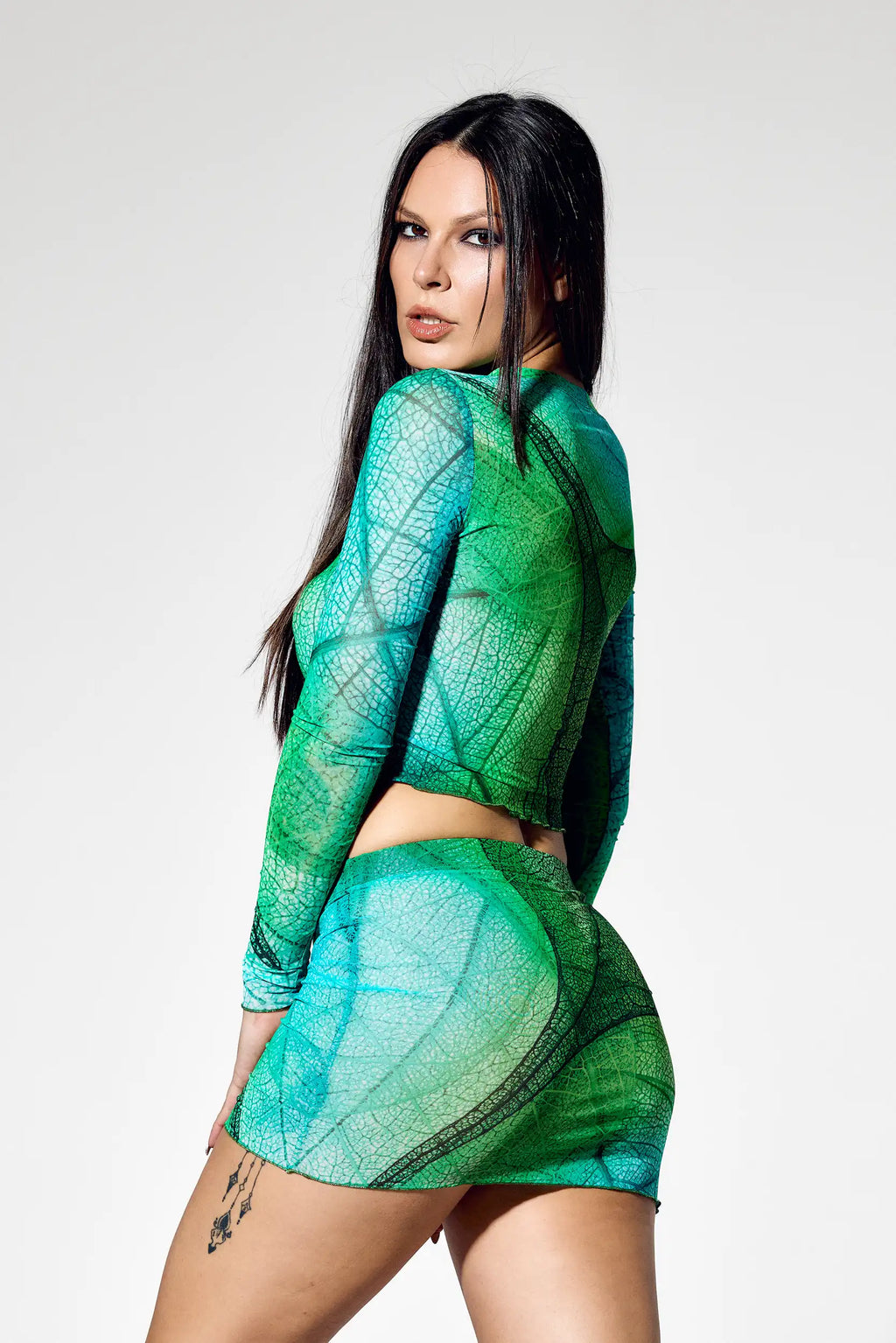 Side pose of futuristic green two piece rave outfit with sheer mesh fabric