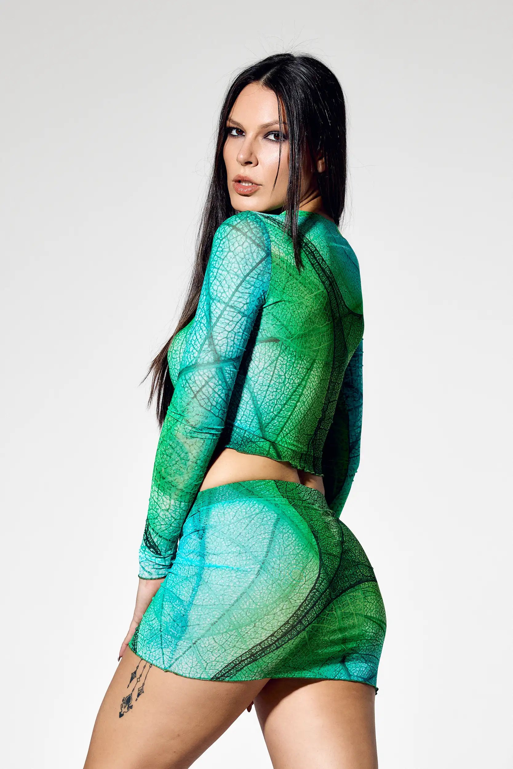 Side pose of futuristic green two piece rave outfit with sheer mesh fabric