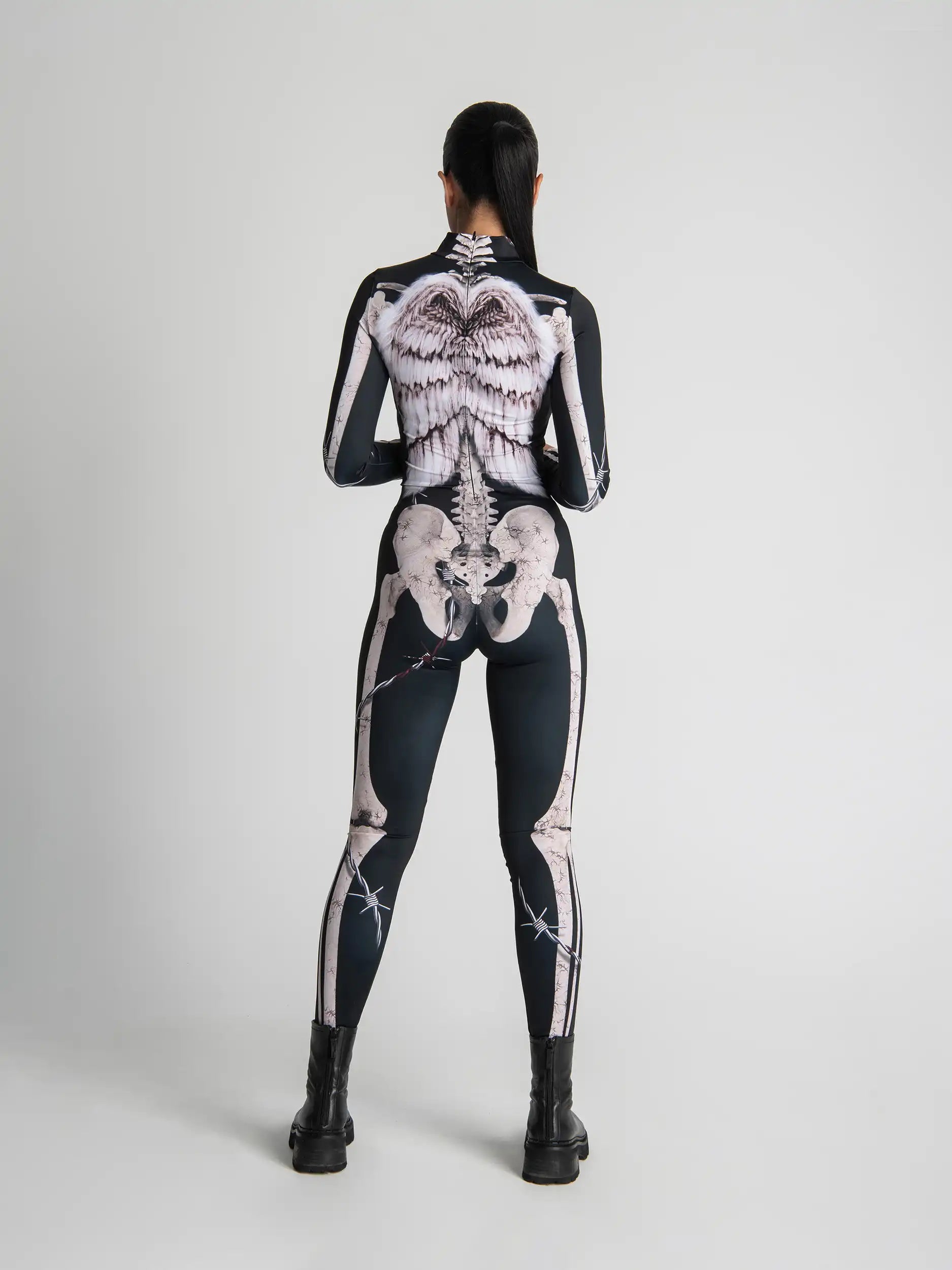 Person wearing a black bodysuit with white skeleton design on a plain background