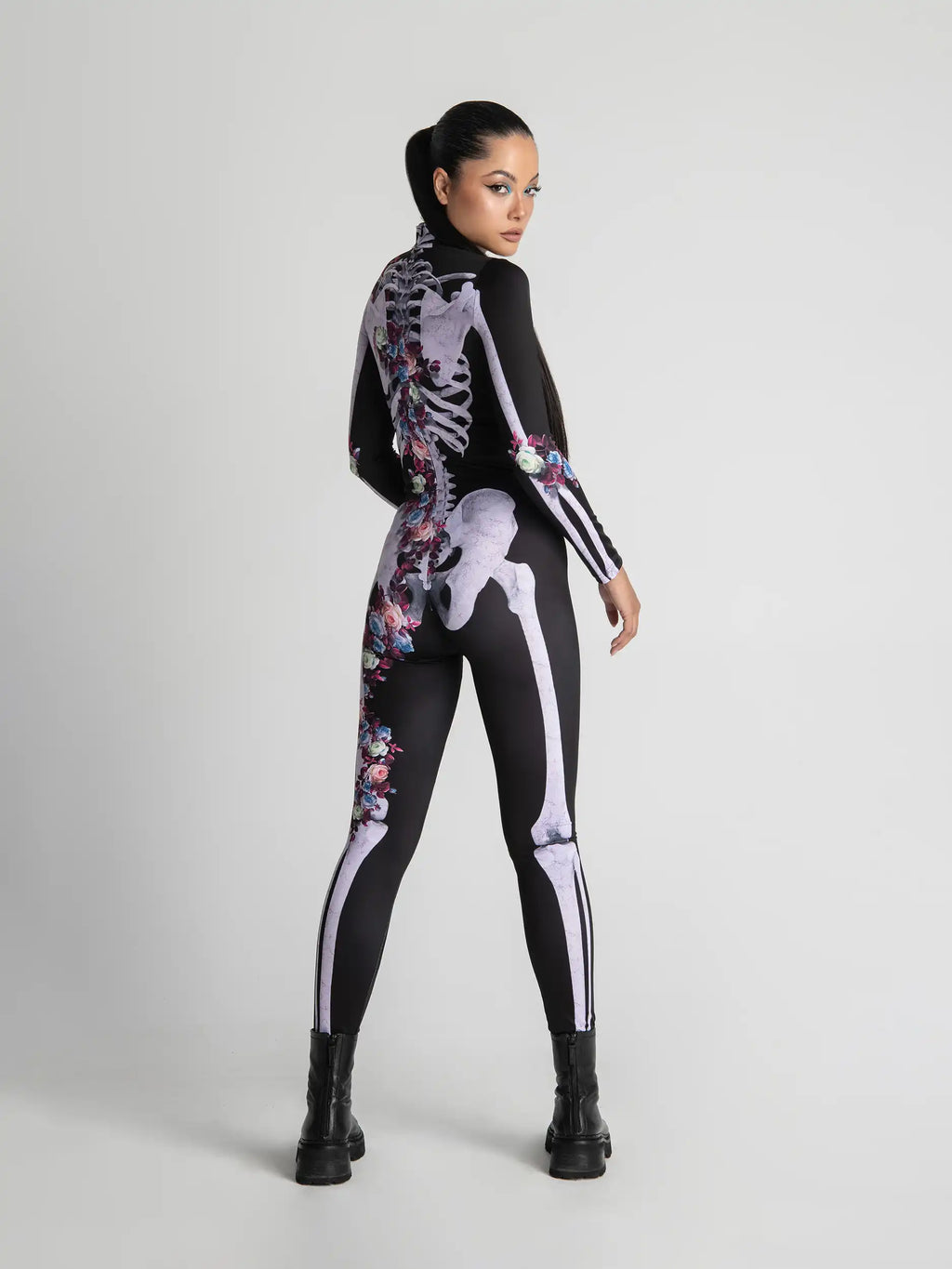 Person wearing a black bodysuit with white skeleton design and floral patterns on a light gray background