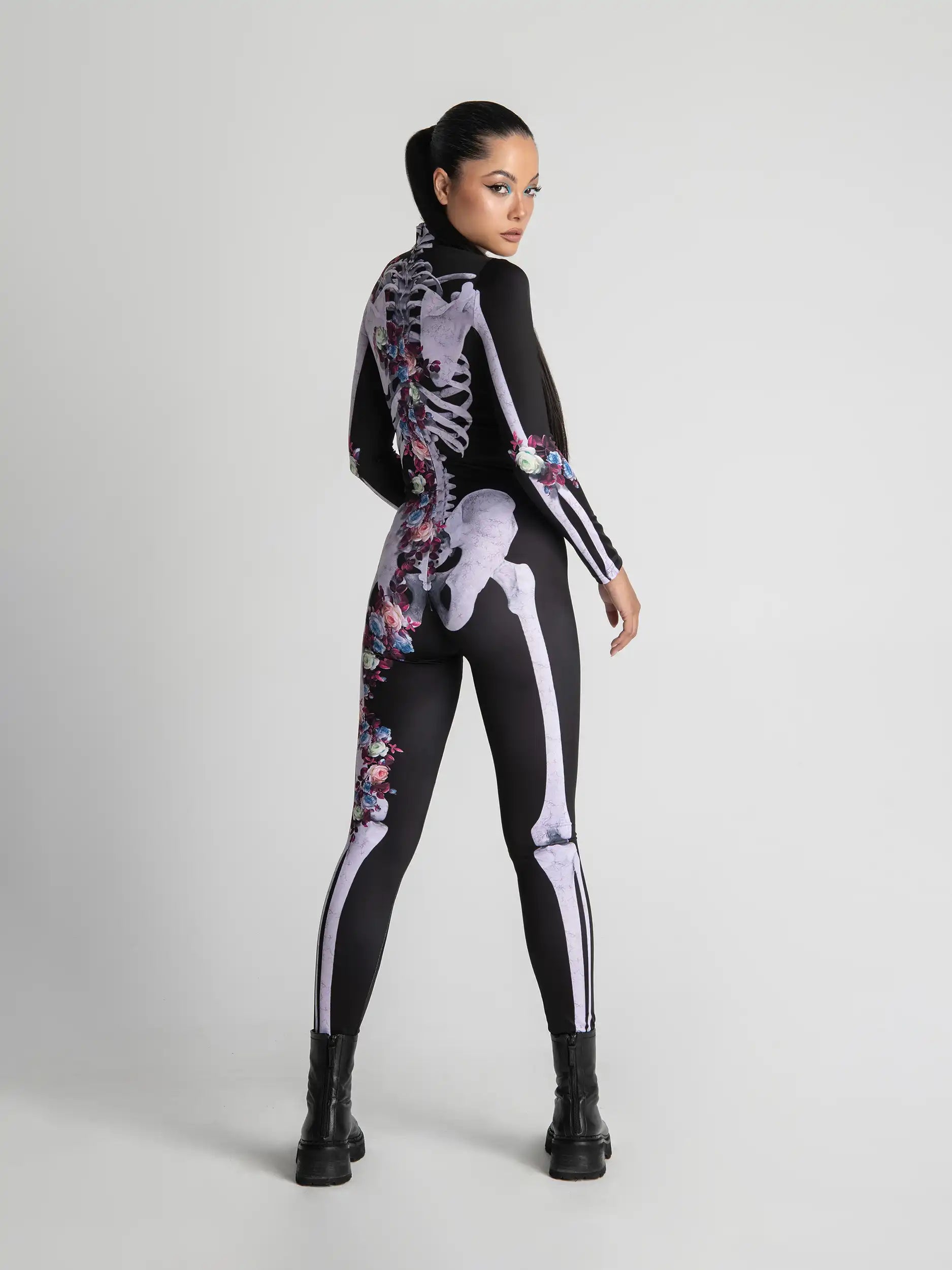 Person wearing a black bodysuit with white skeleton design and floral patterns on a light gray background