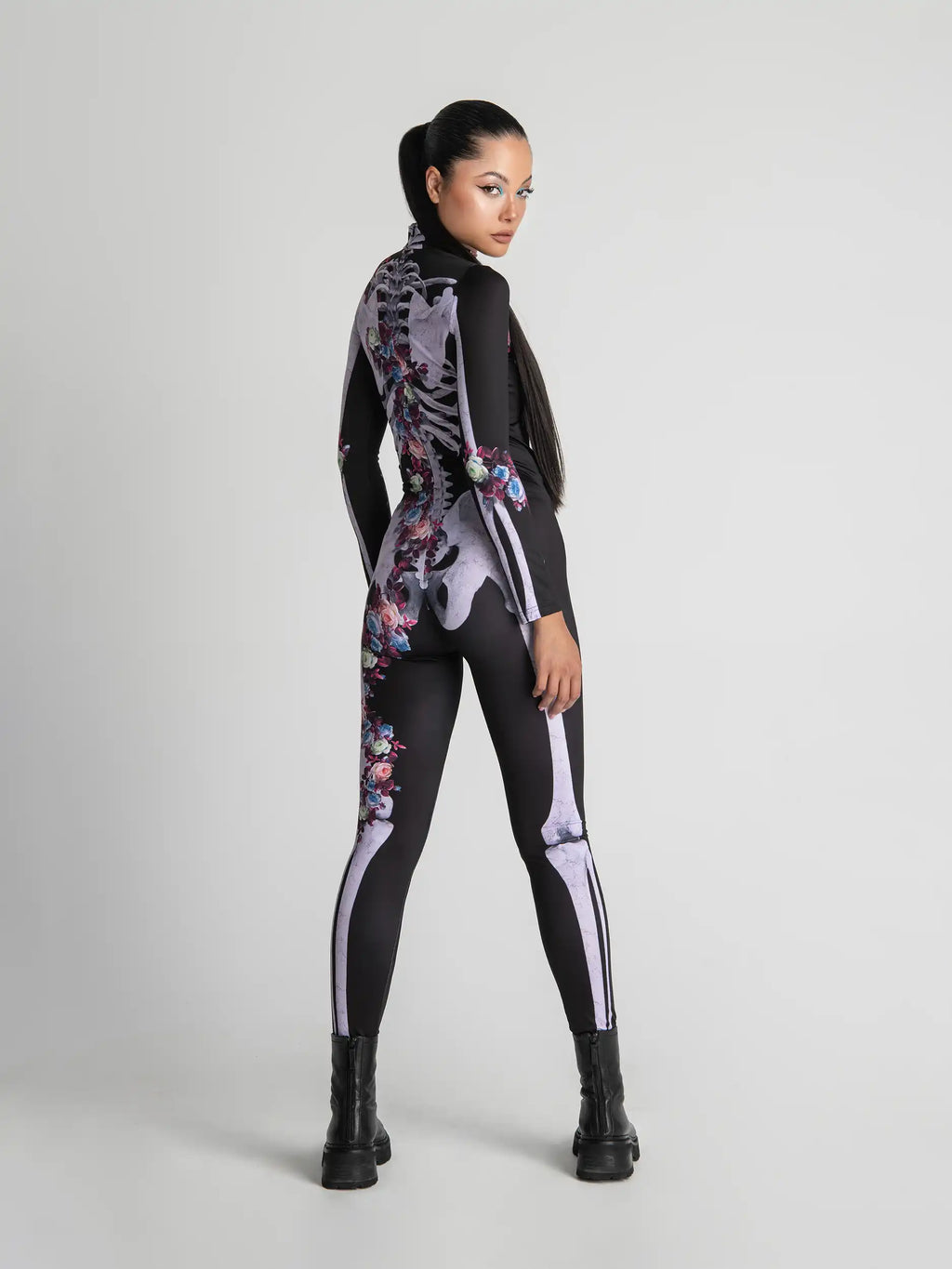 Person wearing a black bodysuit with floral and skeleton designs on a white background