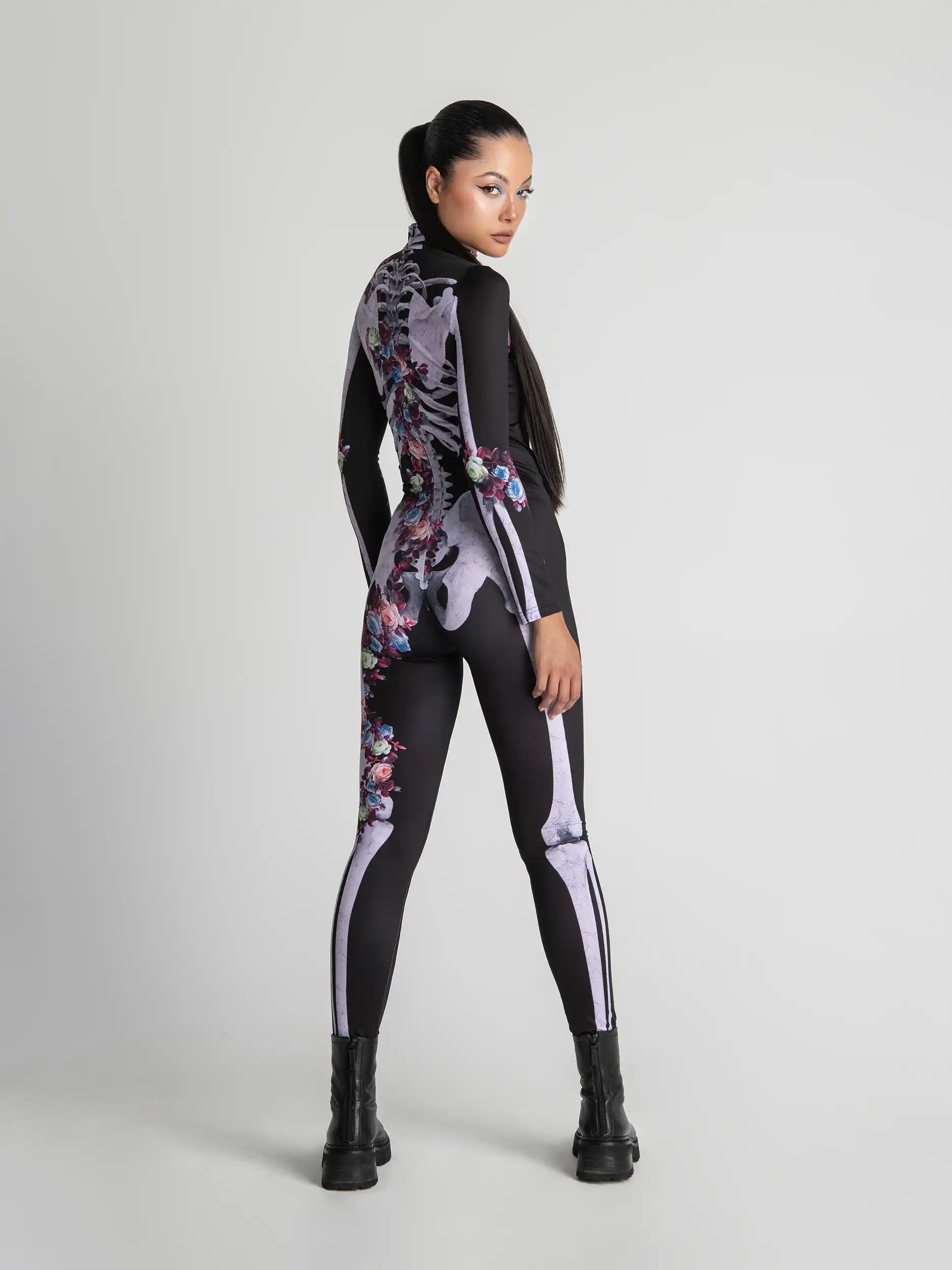 Person wearing a black bodysuit with floral and skeleton designs on a white background