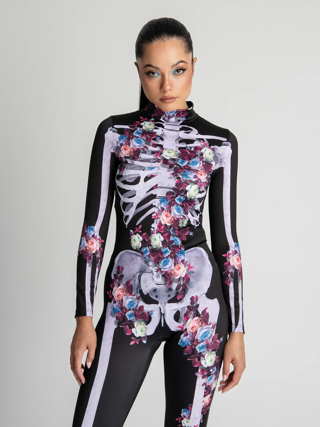Model wearing a black bodysuit with floral and skeleton design on a gray background