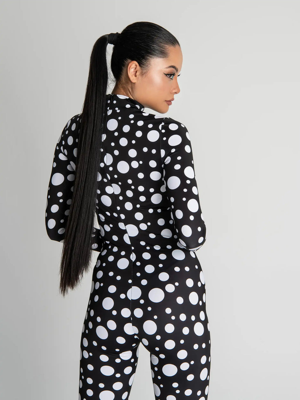 Woman wearing a black and white polka dot outfit on a plain background