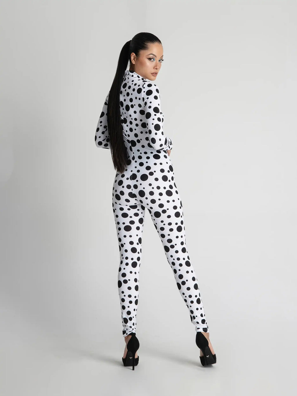 Person wearing a black and white polka dot outfit on a gray background