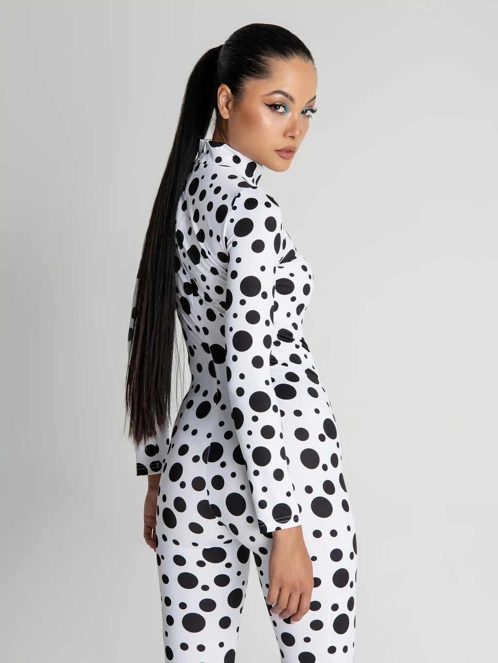 Person wearing a black and white polka dot outfit on a gray background